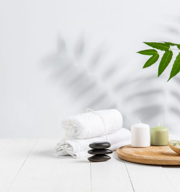 Beautiful spa composition on massage table in wellness center, copyspace. Accessories for relaxing treatments and personal care. Towels, oils, serum, sea salts and scrubs. Decorative candles.